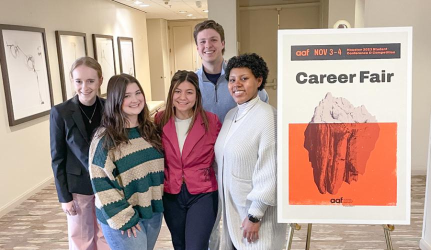 SFA marketing and public relations students stand next to an American Advertising Federation competition poster