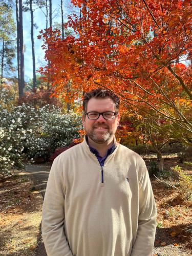 Dr. Andrew King stands in front of colorful fall foliage at the SFA Gardens.