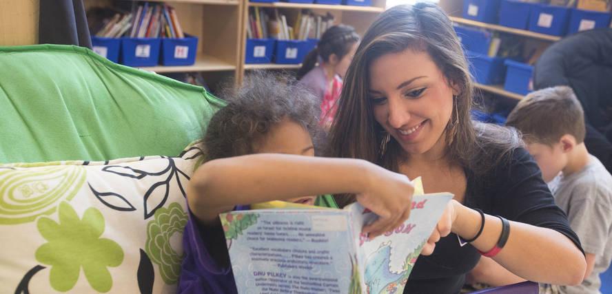 An SFA student helps a child with her reading skills