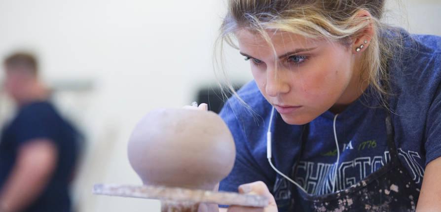 An SFA art student works with clay on a ceramics project