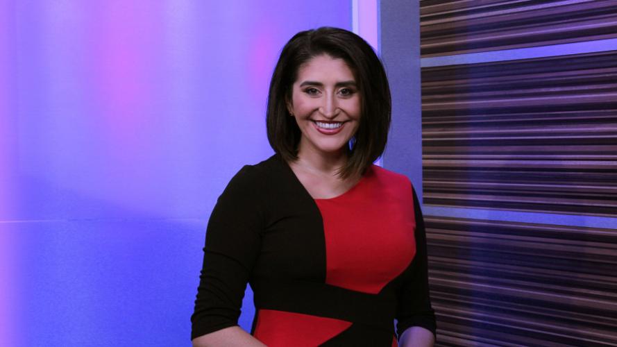 Erika Bazaldua Holland is pictured in a newsroom with purple background lighting