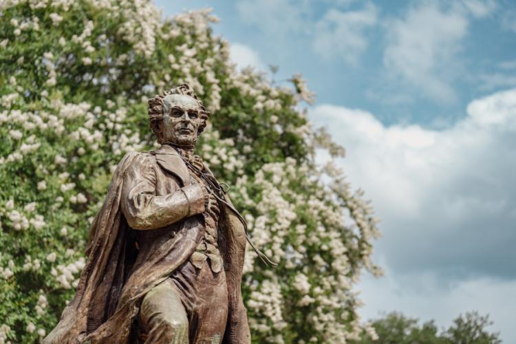 A statue of Stephen F. Austin stands against a background of trees