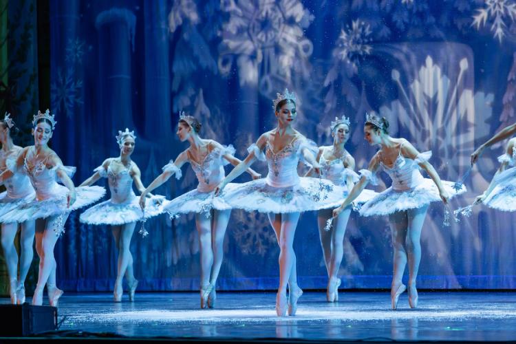 Ballet dancers perform on stage with a wintry backdrop