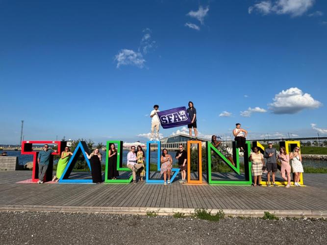 SFA students pose around a sculpture made of the letters T-A-L-L-I-N in Estonia