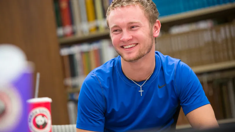 student in blue shirt wearing cross smiles