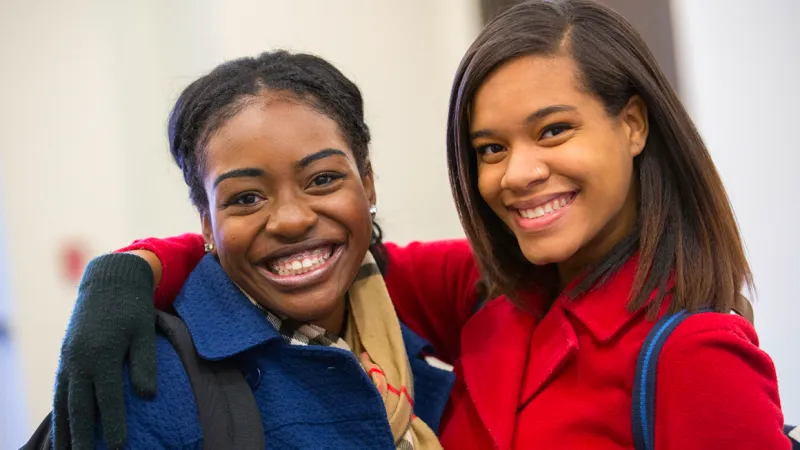 Two students smile at the camera