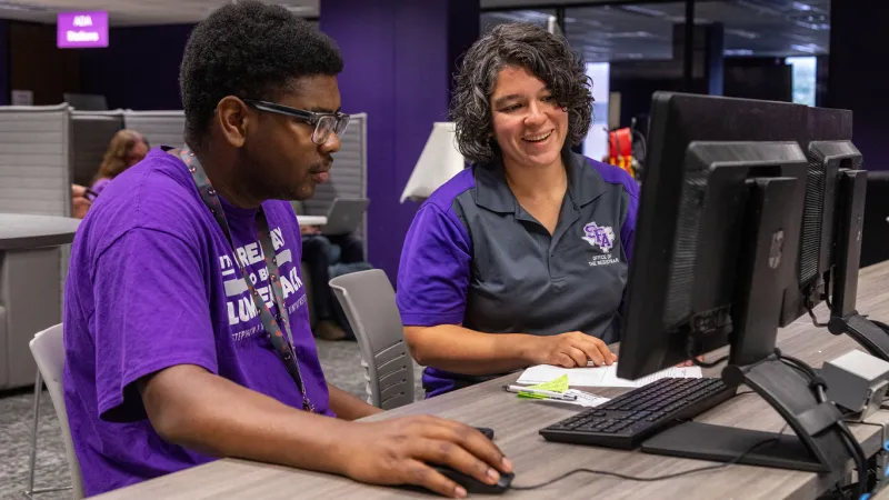 Student receiving guidance to register for classes on computer