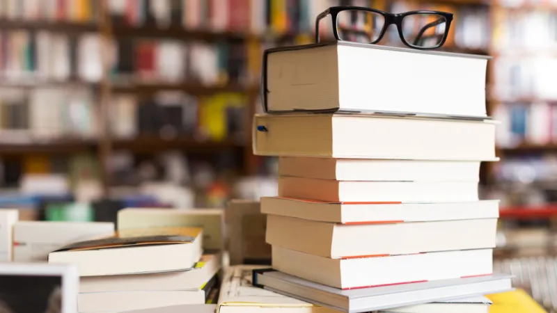 glasses on top of stack of art books lying on table in bookstore