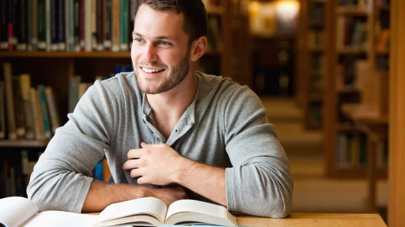 Smiling male student working in a library