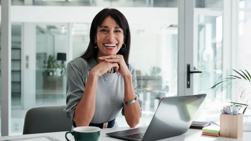 Portrait, woman and smile in office with laptop for public relations, career development or pride. Confident, mature person and happy in workplace with computer