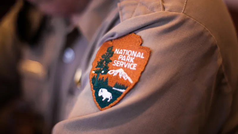 Badge with the Logo of the National Park Service on a Shirt of a Ranger