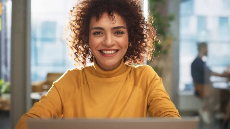 Woman with brown hair and yellow top smiling at the camera