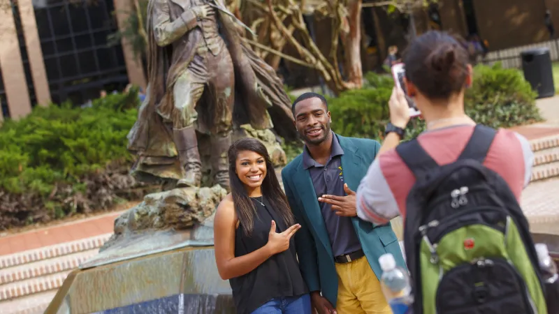 Two students posing in front of the fountain with their axes up