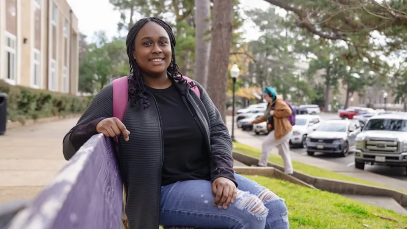 Student sitting on a purple bench