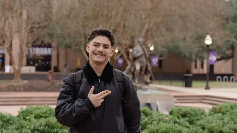 Student standing with Axes Up and fountain in the background