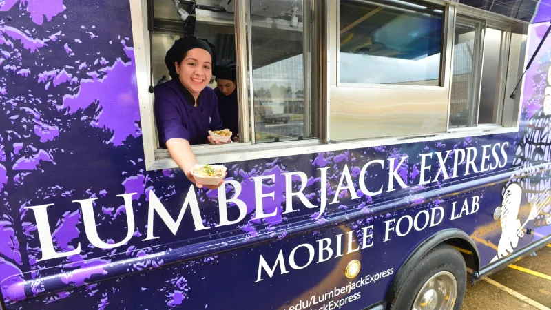 Student offering food from mobile food lab