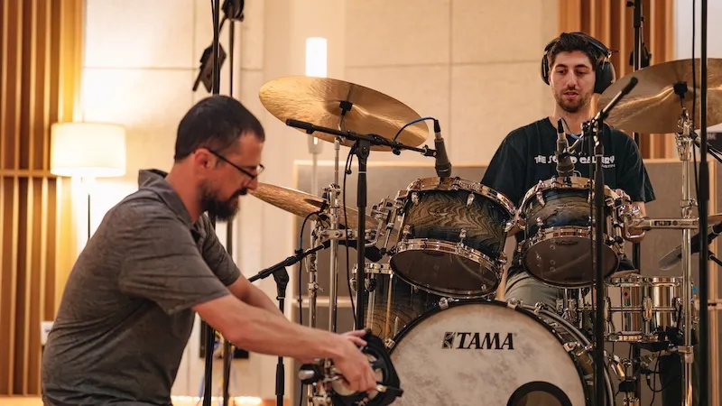 Setting up recording equipment around a drum set