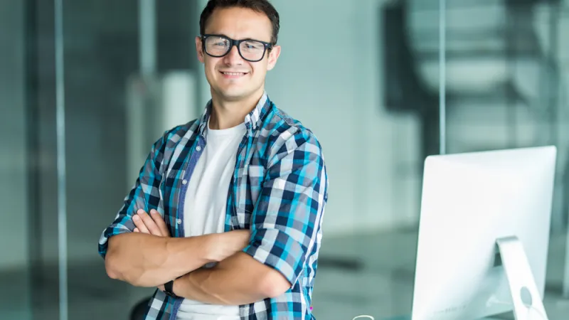 Man standing with arms crossed smiling at the camera