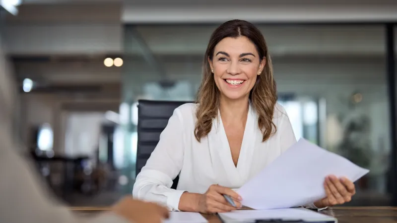 Woman sitting at a desk and smiling at someone off camera