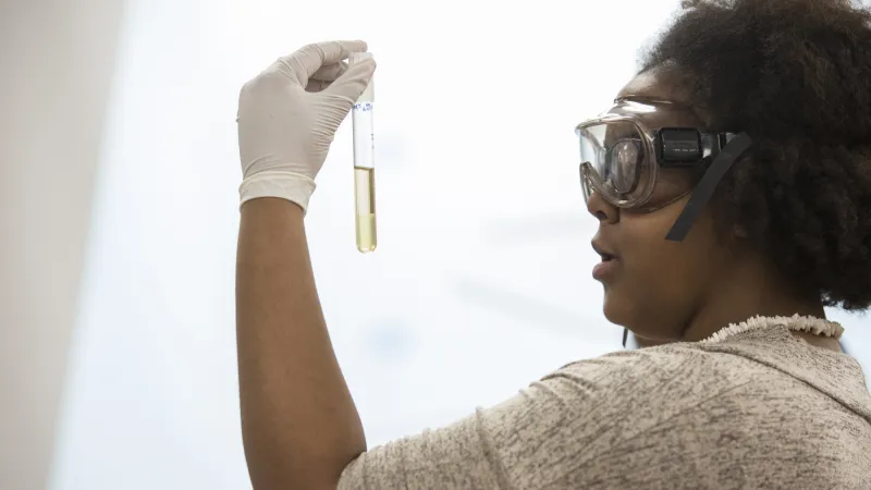 Student wearing safety goggles and inspecting a sample