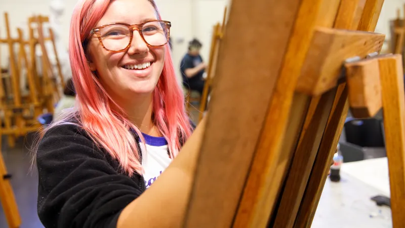 Student smiling at the camera during a drawing class