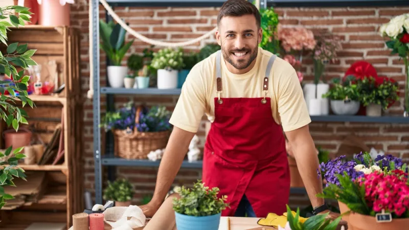 male business owner standing at flower counter and smiling at the camera