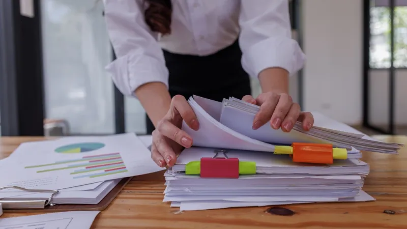 closeup of person sorting through stacks of accounting papers