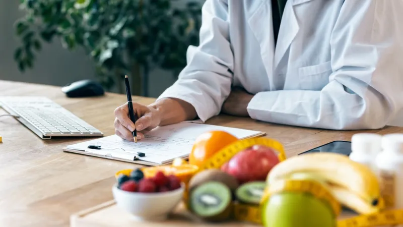 Nutritionist taking notes at a desk with a tray of fruits and vegetables