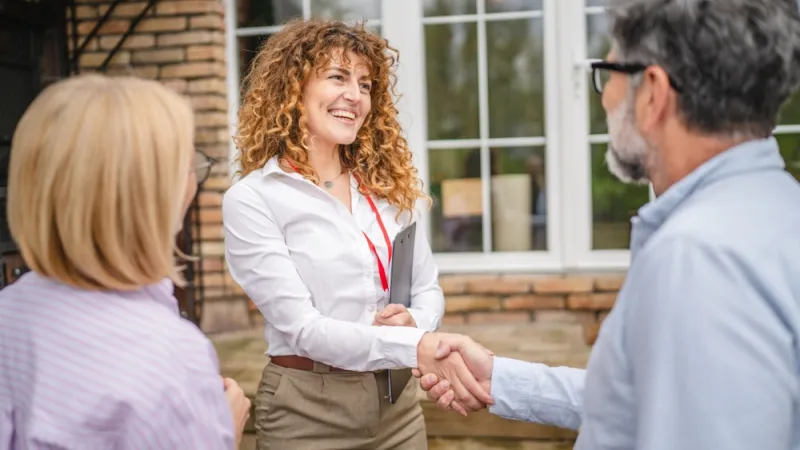 woman holding a folder and shaking hands with a male client