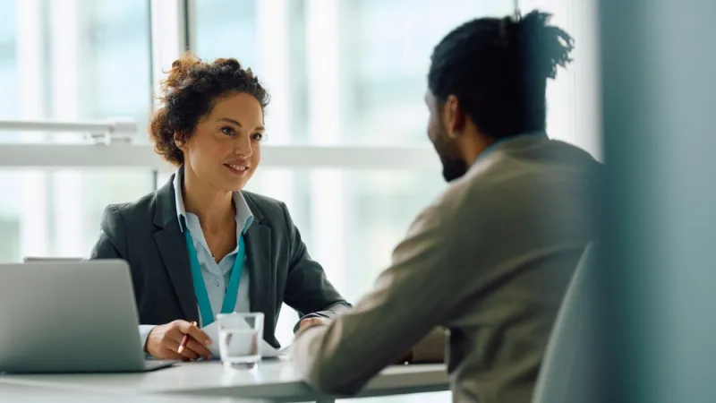 man and woman having a meeting at a desk with a laptop