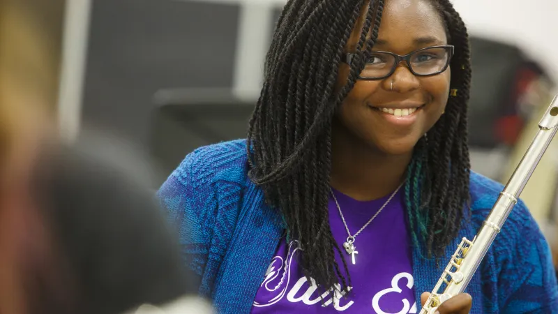 SFA student holding a flute and smiling at the camera