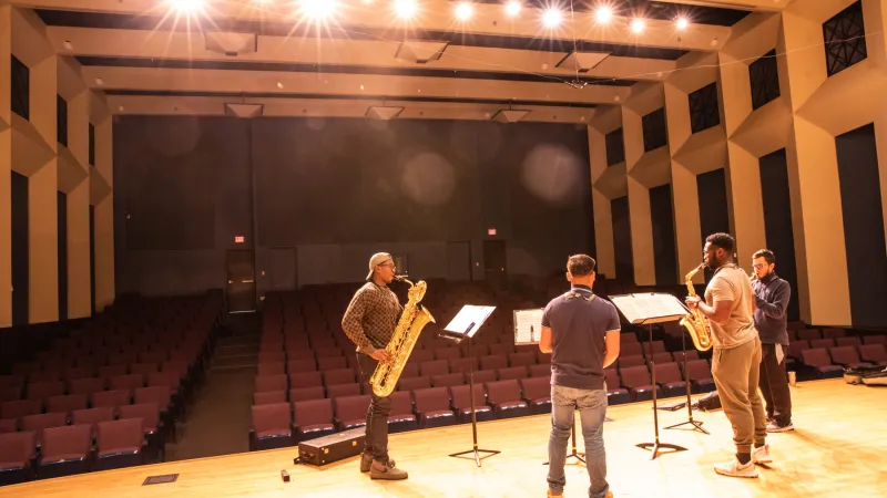 Four students practice their ensemble performance on a stage