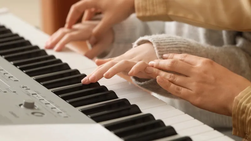 Closeup of instructor guiding a student's hands to proper piano placement