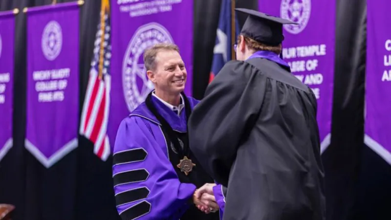 SFA President Neal Weaver shakes a graduate's hand