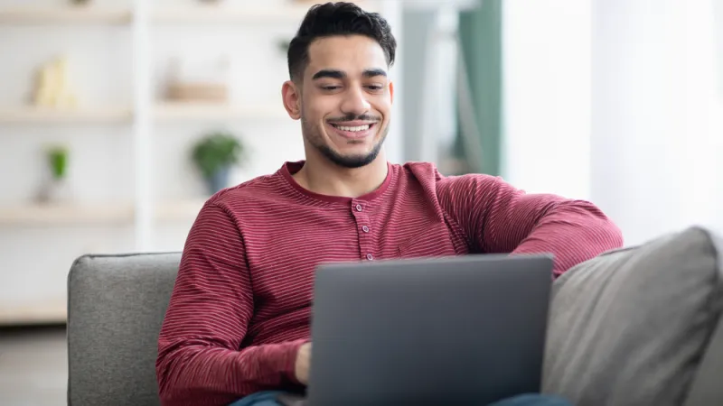 Man sitting on couch looking at laptop