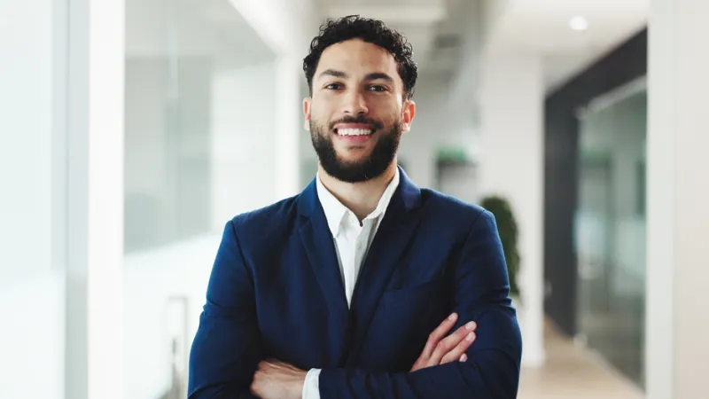 Male standing with arms crossed and smiling at camera