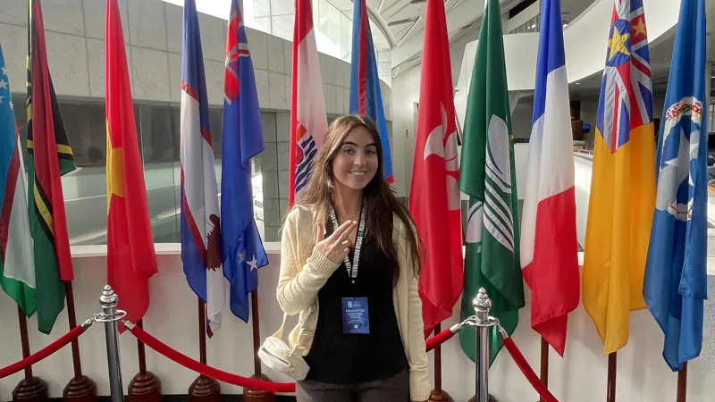 Kara Eaton gives the SFA "Axe 'em" hand sign in front of a row of country flags.