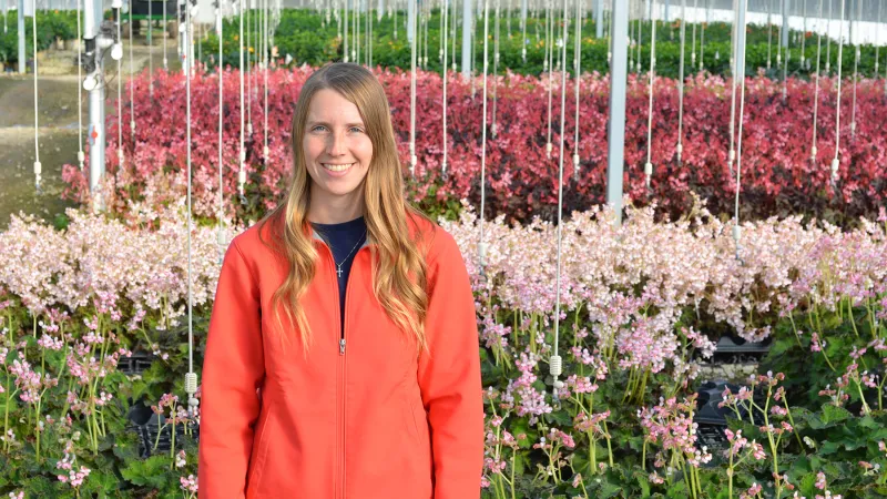 Brooke McGown stands against a backdrop of flowers in a nursery