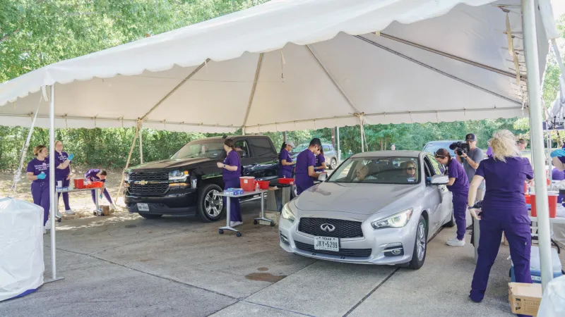 SFA School of Nursing students provide flu shots to car passengers underneath a large canopy