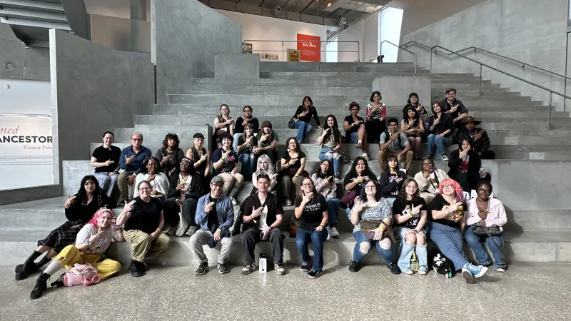 Over three dozen SFA art students and faculty members line a broad concrete stairway, giving the SFA axe 'em hand sign