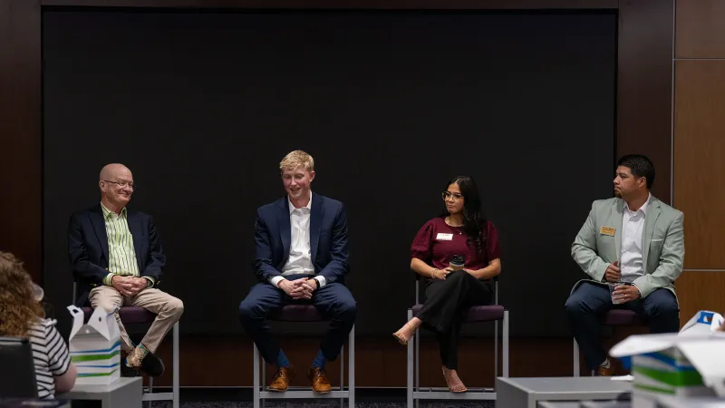 Four panel members sitting on stools discuss topics in banking