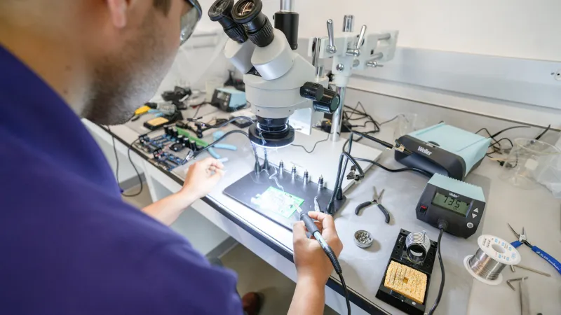 An SFA student solders components onto a circuit board