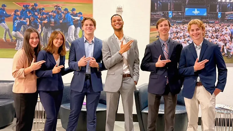 Members of SFA's Sports Business Society dressed in business casual attire give the Axe 'Em hand sign