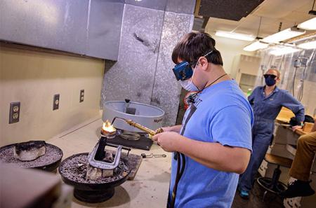 Burgess recycles sterling silver scraps by melting them in a crucible and pouring the metal into a wire ingot mold during his SFA metalsmithing class.