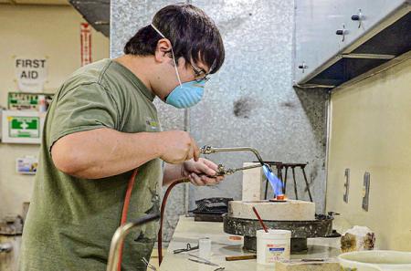 Using two air/acetylene torches, Burgess silver solders a hollow construction ring.