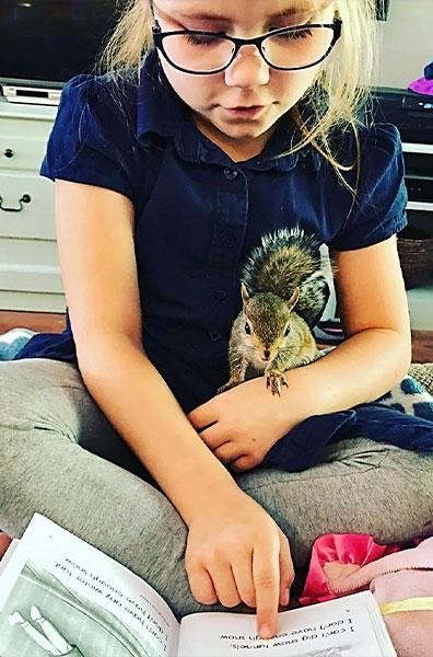 The squirrel enjoys book time with Chloe Prunés. Photo courtesy of DeAnna Prunés.