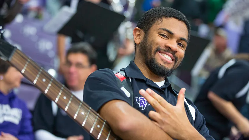 An electric bass player gives the axe em hand sign