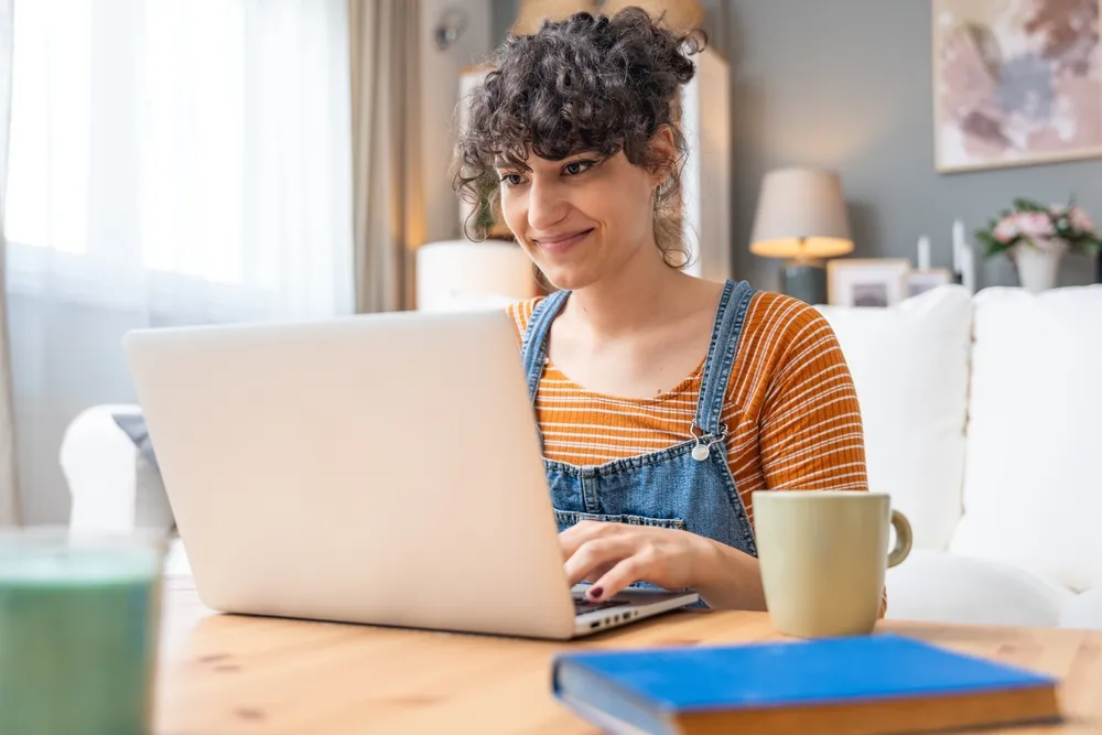 Young happy and confident woman using laptop computer at home