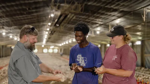 Students and faculty member holding chickens