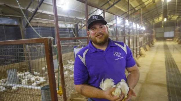 Student smiling at camera holding chickens